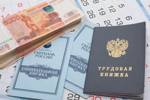Anapa, Russia - 29.06.2020: The calendar contains a work book, a savings book and a large bundle of five thousandth Russian bills