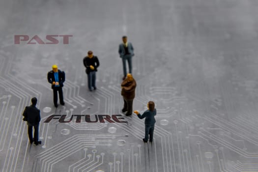 Miniature figurines posed as business people in a meeting over abstract futuristic circuit board with text Past versus Future