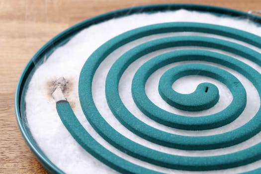 Classic green mosquito coil in a metal plate on table