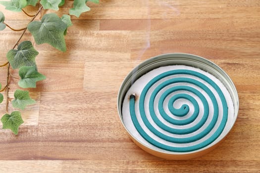 Classic green mosquito coil in a metal plate on table