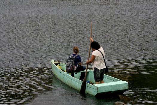 ilheus, bahia / brazil - june 20, 2011: woman is seen rowing a boat while crossing the Cachoeira river in the city of Ilheus, in the south of Bahia.