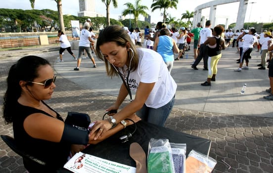 itabuna, bahia / brazil - march 23, 2012: nursing technician measures blood pressure in person in the city of Itabuna, during social action.