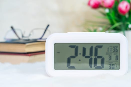 Close up Digital clock with book stacked on table