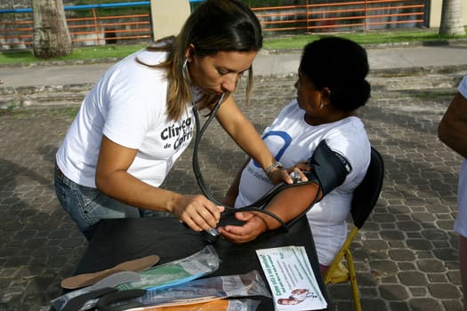 itabuna, bahia / brazil - march 23, 2012: nursing technician measures blood pressure in person in the city of Itabuna, during social action.