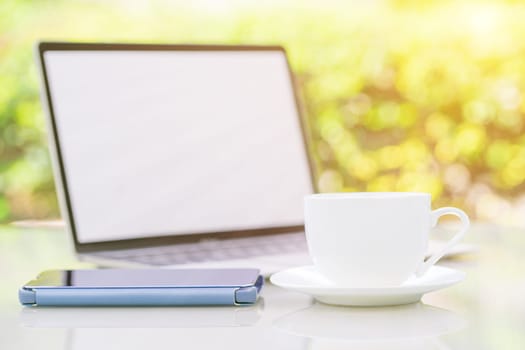 Close up coffee cup and laptop on table at office with smartphone