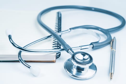 Close up Medical stethoscope for doctor checkup on health medical laboratory table with notepad as medical concept