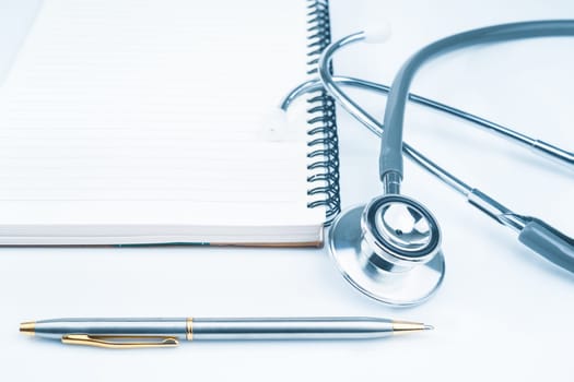 Close up Medical stethoscope for doctor checkup on health medical laboratory table with notepad as medical concept