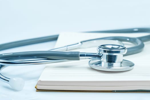 Close up Medical stethoscope for doctor checkup on health medical laboratory table with notepad as medical concept