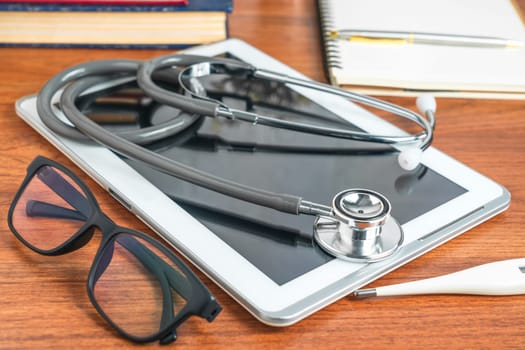 Medical stethoscope for doctor checkup with tablet computer on doctor table as medical concept