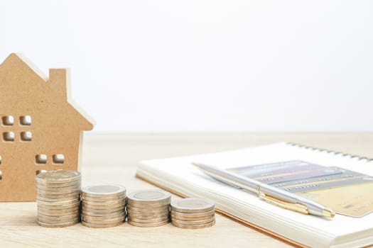 House model and notepad with coins on table for finance and banking concept