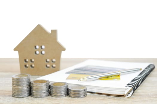House model and notepad with coins on table for finance and banking concept