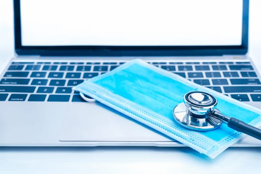 Medical stethoscope for doctor checkup on laptop with medical face masks as medical concept