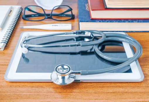 Medical stethoscope for doctor checkup with tablet computer on doctor table as medical concept