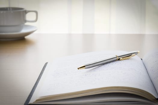 Pen put on a book with on the desk, .Natural light from window