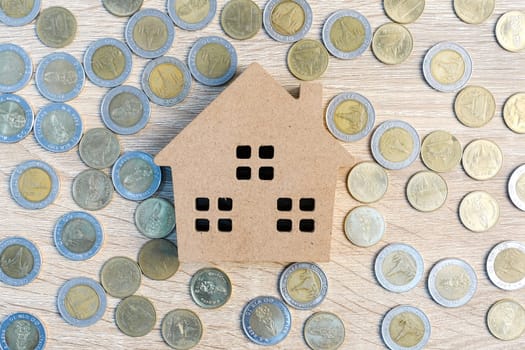 Top view house and coins on wood table using as property real estate and financial concept