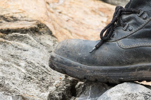 Closeup of trekking leather boot on the rock in mountain