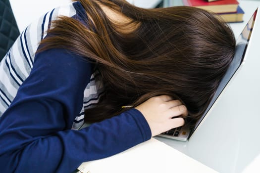 Young woman long hair tired from studying online and fall asleep on desk with laptop