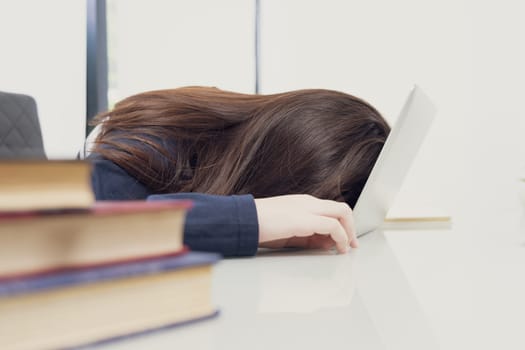 Young woman long hair tired from studying online and fall asleep on desk with laptop