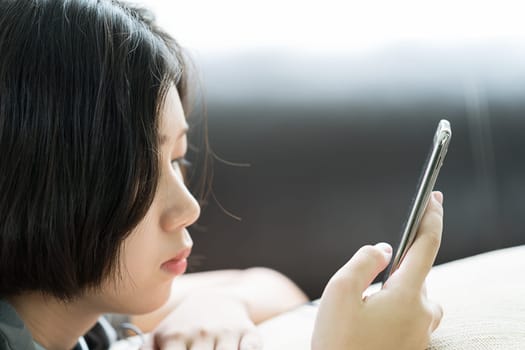 Close up young asian woman short hair listening music from mobile phone on the couch