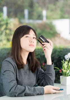 Young woman sitting showing credit card and holding smartphone for online shopping,Online shopping concept