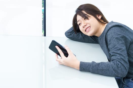 Young woman long hair using mobile phone on workplace close up