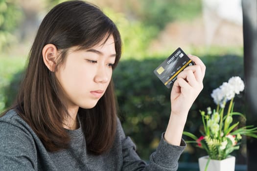 Young woman sitting showing credit card and holding smartphone for online shopping,Online shopping concept
