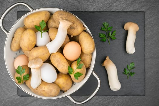 Two King Trumpet Mushrooms and a white and a brown egg on a slate slab. With copyspace. Flat lay.