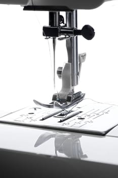 9 - Vertical close up macro image of bright needle and sewing machine working area.