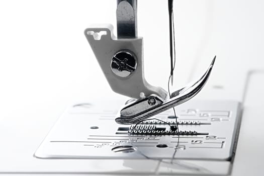 2 - Needle point and thread in macro side view of sewing machine feed dogs and throat plate.