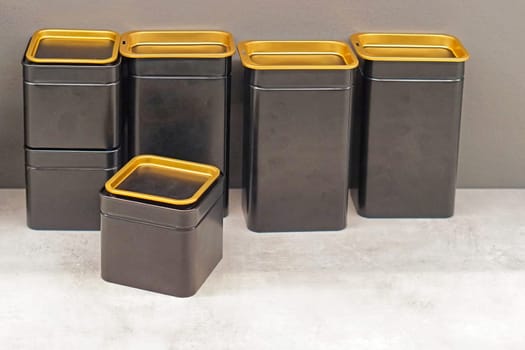 Black boxes with gloden lids at kitchen countertop