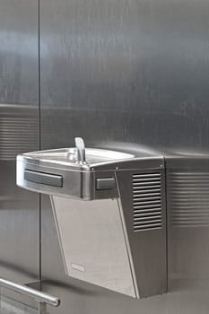 Stainless steel drinking fountain mounted at wall