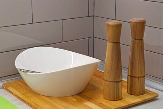 Ceramic salad bowl and grinders at wooden tray kitchen set