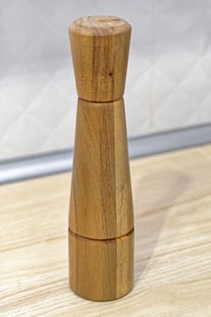Tall wooden pepper grinder at kitchen countertop