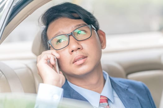 Young asian business men portrait in suit working in the backseat of a car