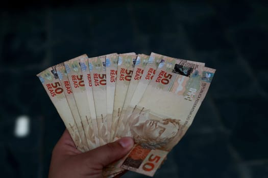 salvador, bahia / brazil - february 25, 2015: hands hold fifty reais (R $ 50.00) bills in the city of Salvador......