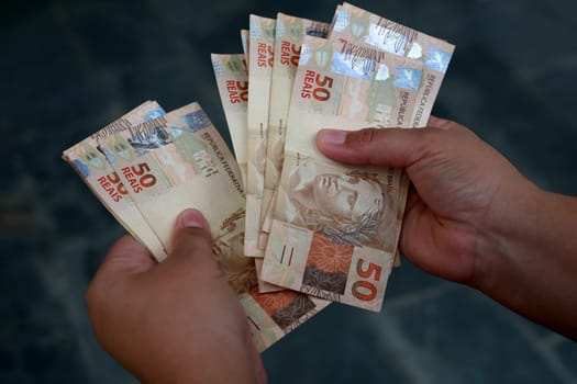 salvador, bahia / brazil - february 25, 2015: hands hold fifty reais (R $ 50.00) bills in the city of Salvador......