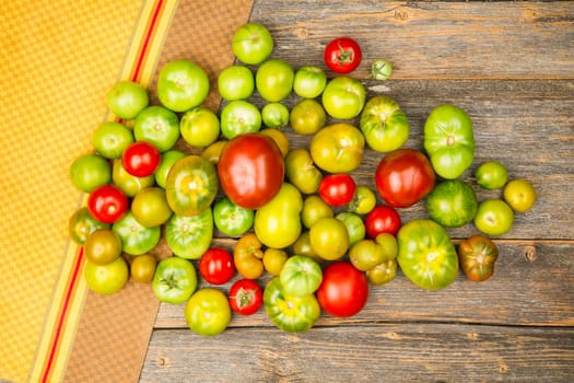 Heap of different sorts of tomatoes on a wooden table