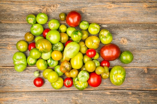 Heap of different sorts of tomatoes on a wooden table