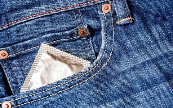 A condom pops out of the front pocket of a pair of jeans. Prevention of sexually transmitted diseases. Safe sex