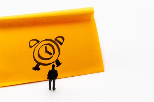 Miniature figurine posed as businessman in front of handrawn clock on adhesive paper note, time management concept image