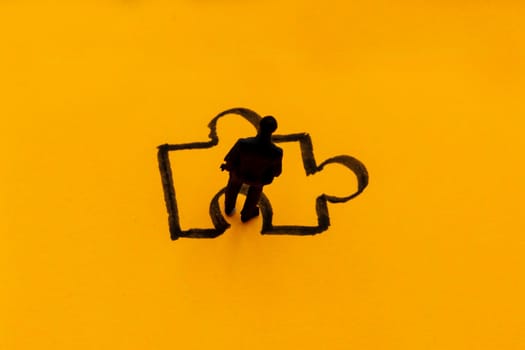 Miniature figurine posed as businessman in front of puzzle piece, solution concept image
