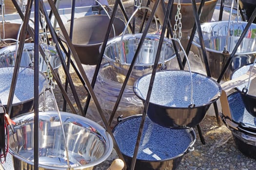 Many new metal cooking cauldrons with tripod legs