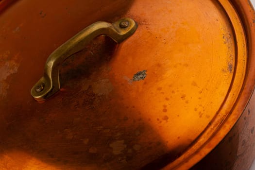 side view closeup detail of old cooking pan with copper lid cover and metallic handle