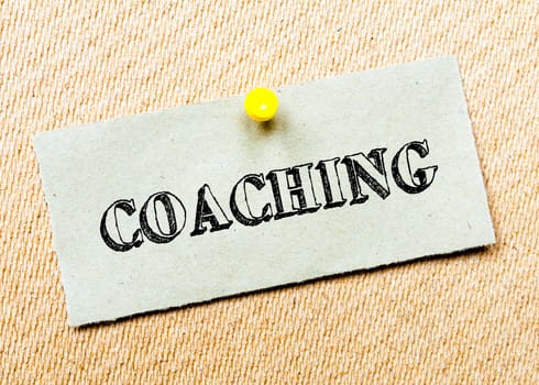 Recycled paper note pinned on cork board.Coaching Message. Concept Image