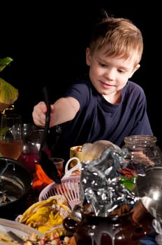 boy with a spoon sits behind dirty table