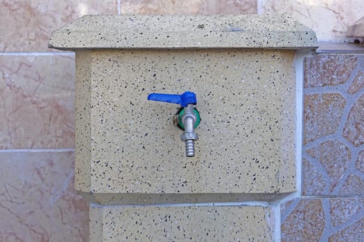 Water faucet with blue handle and hose attachment