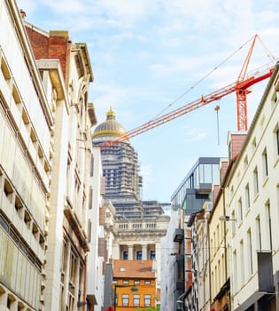 Upward view from central street, reconstruction of The Court of Laws or Palace of Justice, red construction crane. Brussels, Belgium