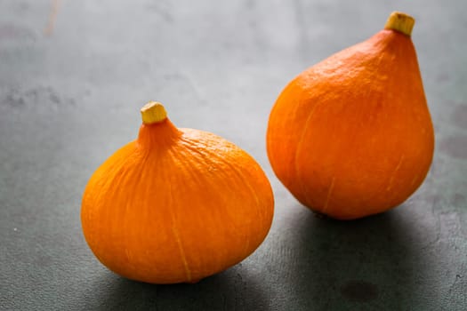 Red kuri squash on green background. Delicious edible pumpkins.