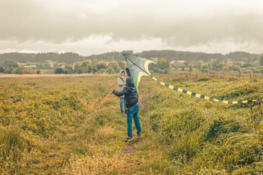 schoolboy and his mother launches a kite into the air in a field