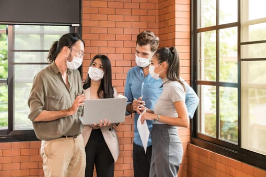 Group of business worker team meeting and brainstorm. They wear protective face mask in new normal office preventing coronavirus COVID-19 spreading.